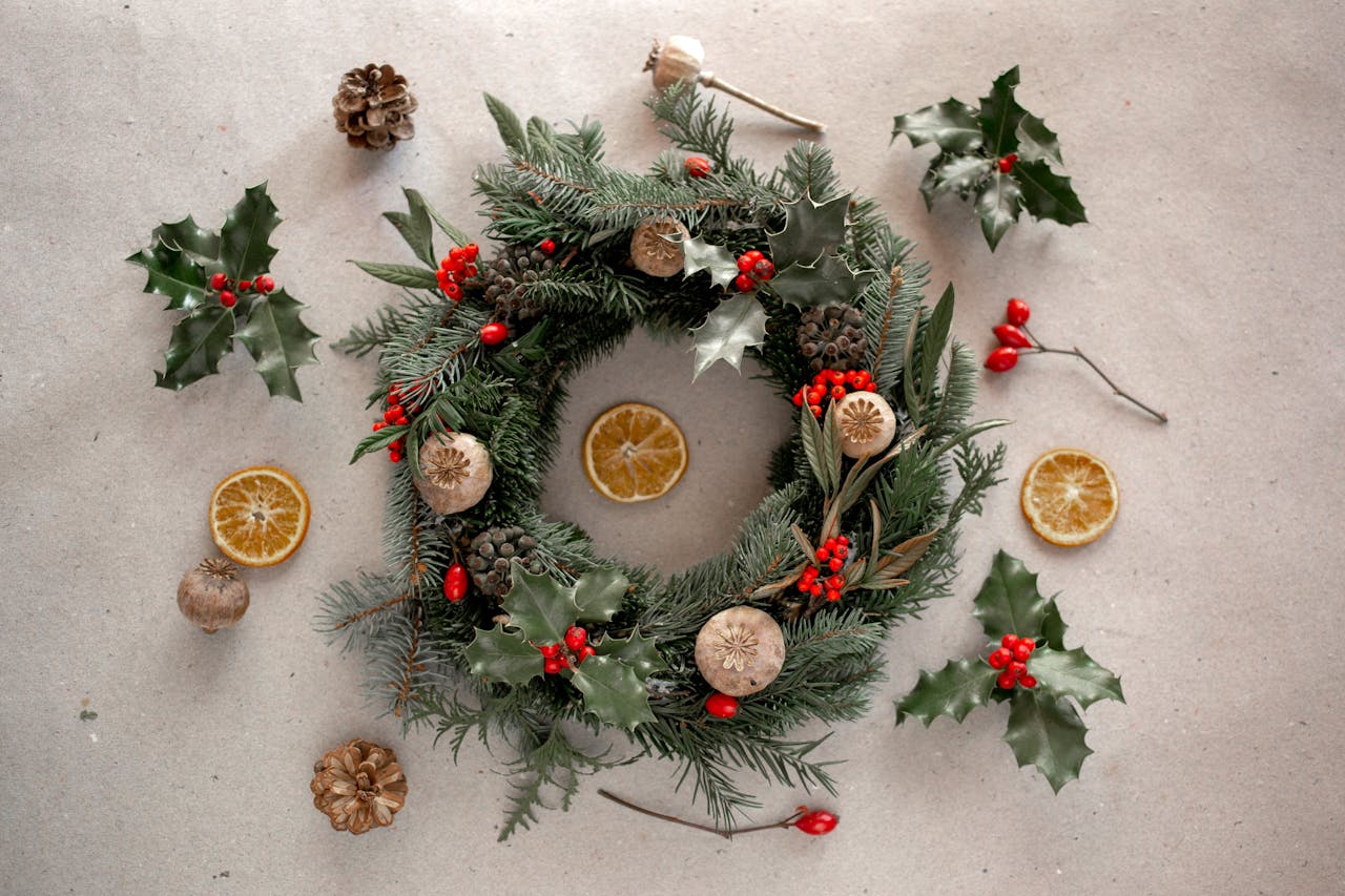 services-03 Rustic Christmas wreath adorned with pine cones, holly, and dried citrus on a neutral background.